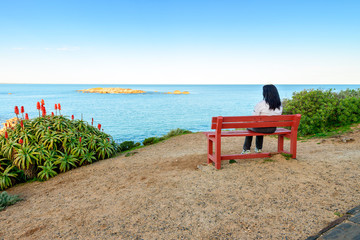 Woman sitting on bench with sea view