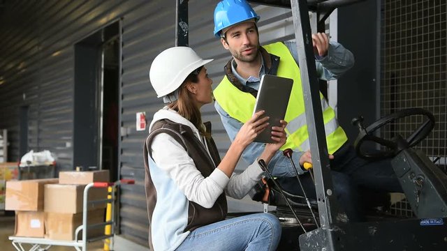 Warehouseman driving cart, listening to operator instructions