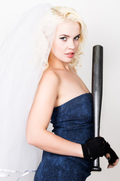 Beautiful blond bride wearing blue dress and weil with professional make-up holding baseboll bat