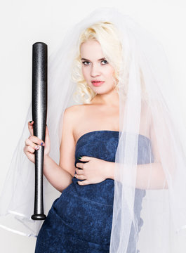 Beautiful blond bride wearing blue dress and weil with professional make-up holding baseboll bat