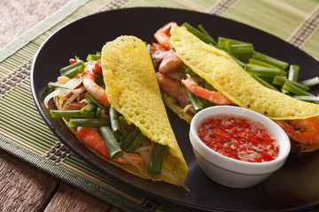 Asian food: crepes with pork, shrimp, onions and bean sprouts and a spicy sauce closeup. Horizontal