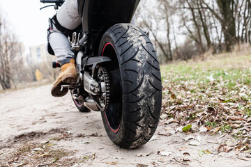Biker sitting on motorcycle, close-up view on rear wheel