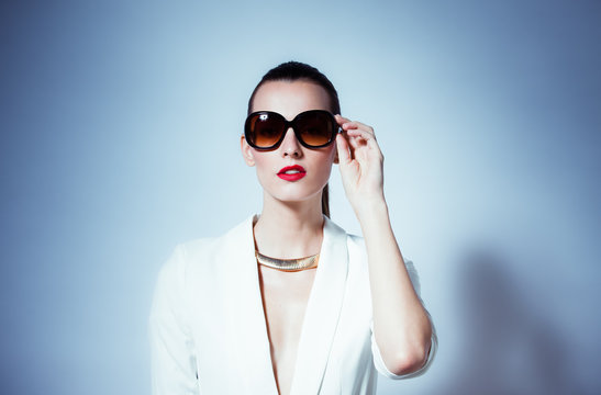 High fashion portrait of girl wearing sunglasses in a studio setting. 