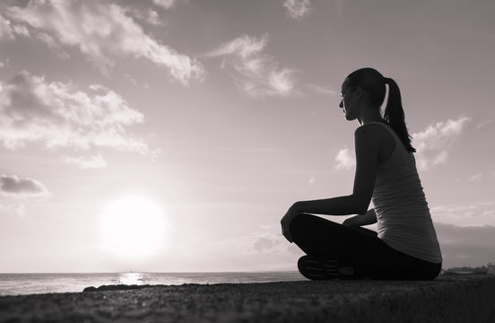 Young girl sitting watching the sunset thinking. 
