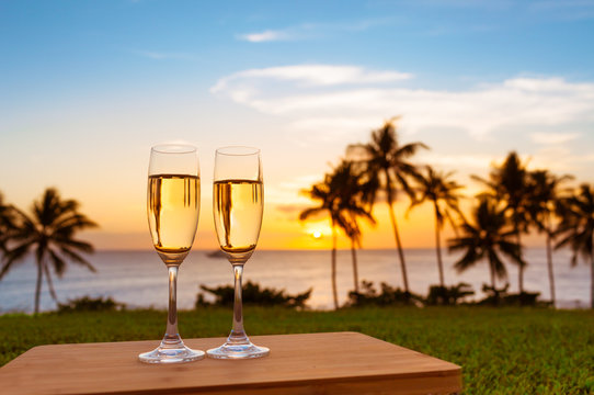 Pair of champaign glasses in a beautiful sunset setting. Romantic getaway and exotic vacation holiday concept. 