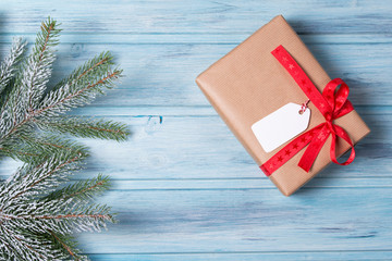 Christmas gift box with tag and fir branch with snow, wooden background, top view