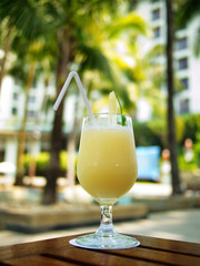 Yellow Pina Colada cocktail on a table on tropical island. Palm