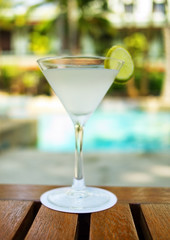 Martini cocktail on a table on tropical island. Palm trees on ba