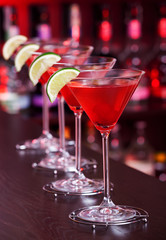Row of Cosmopolitan cocktails shot on a bar counter in a nightcl