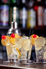 Four Tom Collins cocktails and a sha on a bar in a nightclub. Ve