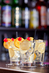 Four Tom Collins cocktails on a bar in a nightclub. Vertical sho