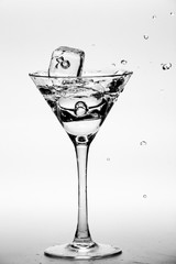 Martini splash with ice cubes shot over grey background