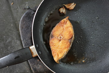 fried mackerel in black pan, little blur, slow speed, swallow deep of field