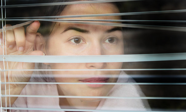 Girl looking through the blinds