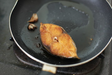 fried mackerel in black pan, little blur, slow speed, swallow deep of field