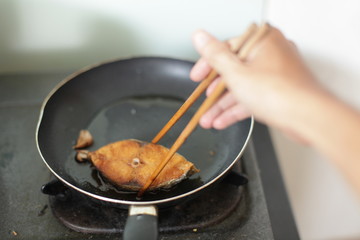 fried mackerel in black pan, little blur, slow speed, swallow deep of field
