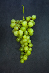 Fresh bunch of green grapes isolated on dark gray slate stone ba