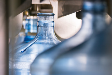 Bottles on conveyor. Big blue jugs. Durable plastic for storing water. Paces of production are growing.