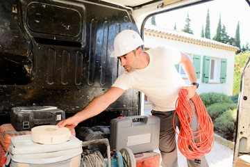 young electrician artisan taking tools out of his professional truck van - obrazy, fototapety, plakaty