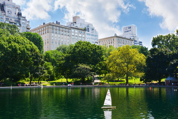 Summer day in Central Park, New York with toy boat on lake