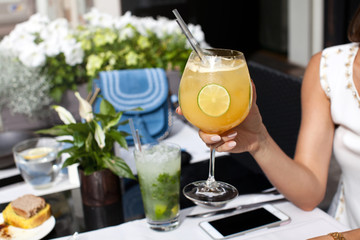 Woman holding tropical cocktail decorated with fresh lime.