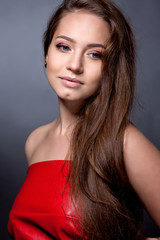 Naklejka premium Portrait of the teenager in a red dress on a gray background.
