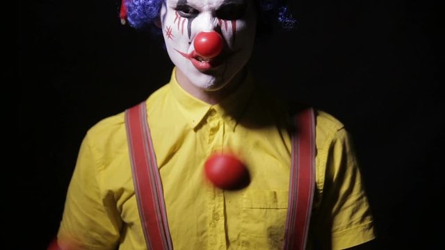 Scary mad Juggler clown using juggling pins. Terrible horror clown. HD.