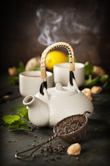 Teapot and cups of tea with mint and lemon