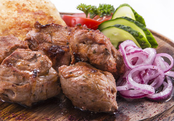 pieces of grilled meat with onion and fresh vegetables