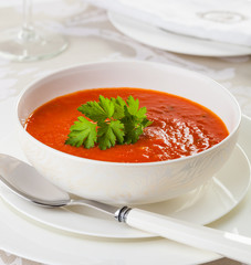 Tomato soup in a white bowl, garnished with parsley,