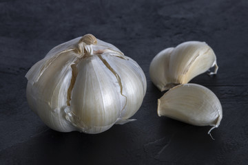 garlic bulbs with garlic cloves  on black wooden background
