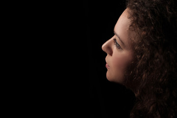 portrait of a beautiful young woman with curly hair on dark background