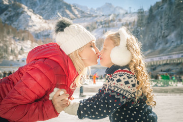 Happy mother and daughter kissing outdoor, ice skating