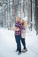 young man presents women Christmas gift in the forest