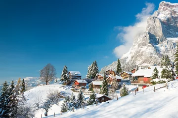 Christmas vacation in Europe. Travel to Switzerland in the winter. Alpine Village in the snow. Traditional houses with red shutters and roofs.