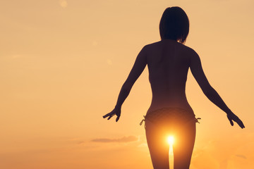 Young woman with short hair standing with sunlight between the legs, sunset or sunrise