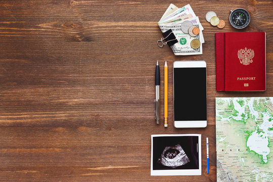 Travel while being pregnant background. Different things you need for journey - smartphone, passport, map, money. Ultrasound photo of baby and positive pregnancy test. Place for text