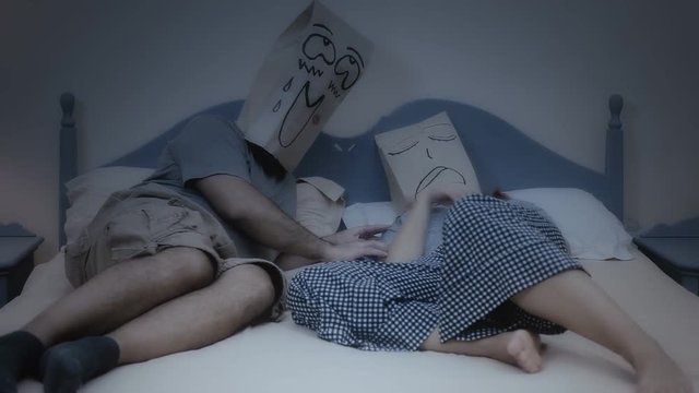 Two breadbag faces in the bed in the night, one is snoring while sleeping, the other is visibly excited.
