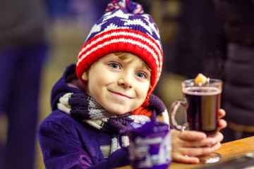 Little kid boy with hot chocolate on Christmas market