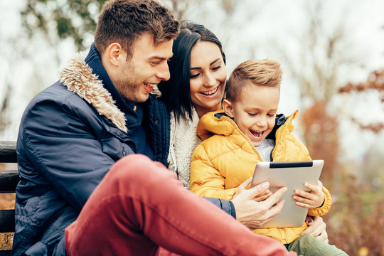 Young Family Having Fun With Digital Tablet In The Park