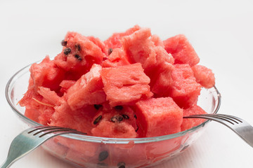 watermelon pieces in bowl with fork on white background