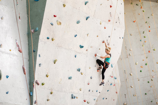Sporty young woman exercising in a colorful climbing gym