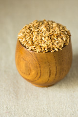 Flax seeds in a wood bowl on linen cloth, close up
