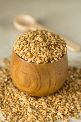 Flax seeds in a wooden bowl with spoon on linen cloth, close up