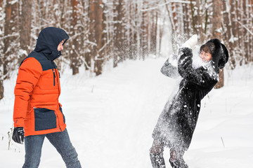 Fototapeta na wymiar Young couple playing in snow, having snowball fight