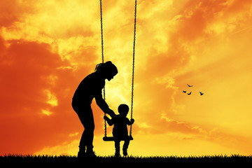 mother and child on swing at sunset