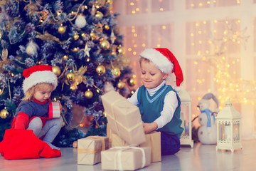 Fototapeta na wymiar Kids opening christmas presents in decorated living room