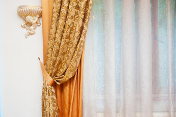 Part of beautifully draped curtain and wall with patterns
