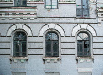 Facade of old abandoned building with three large arched windows