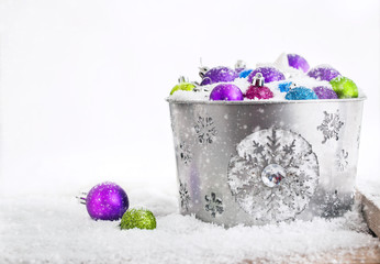 Christmas balls in snow covered bucket